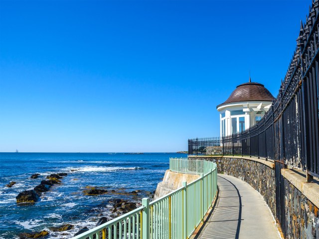 A long walkway next to the coast leading to a rotunda