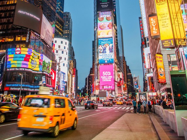 View of busy street and multi-level neon billboard in Times Square, New York City