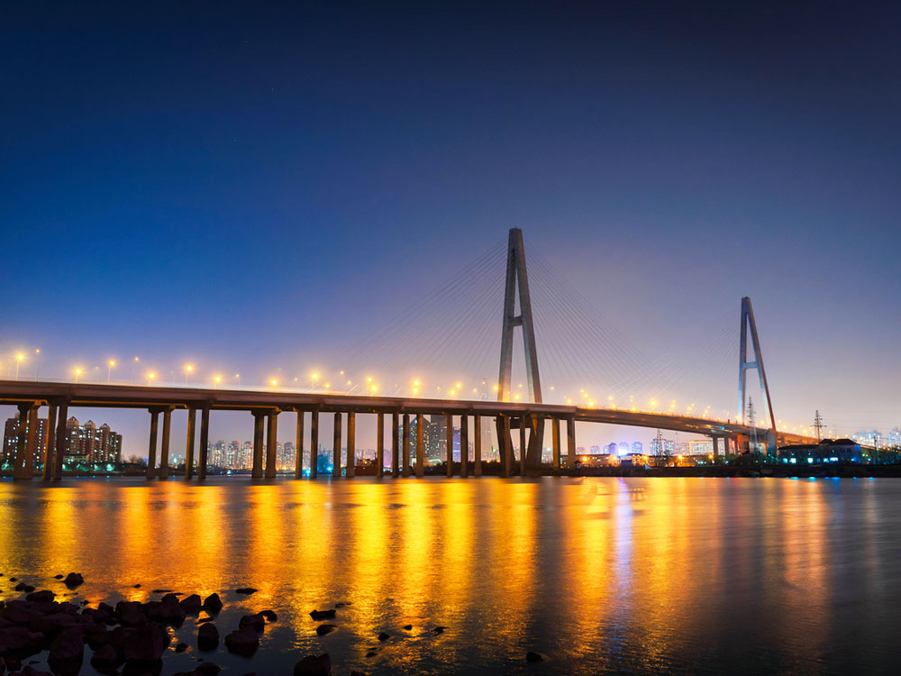 Lights of Tianjin Grand Bridge in China reflecting on water