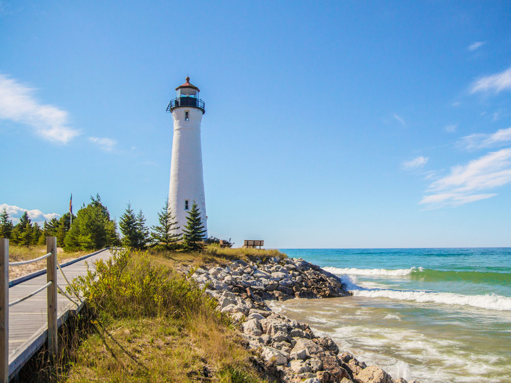 Path leading to white lighthouse on shores of Lake Superior in Michigan