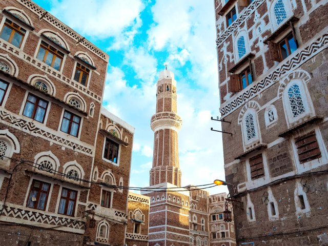 View of mosque framed by red-brick buildings in Sana'a, Yemen