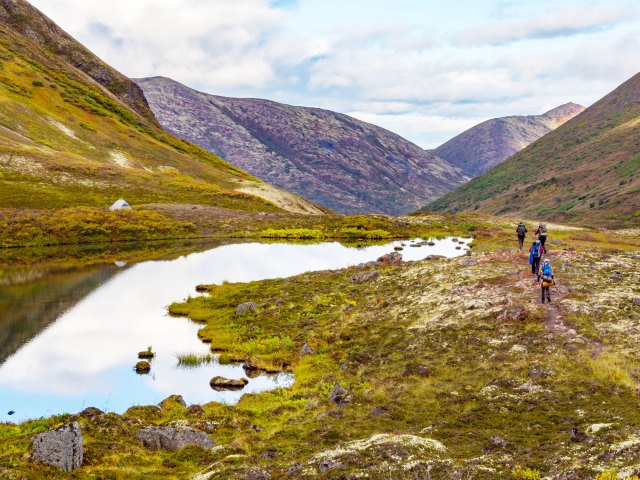 Hikers next to mountain lake in Chugach State Park in Alaska