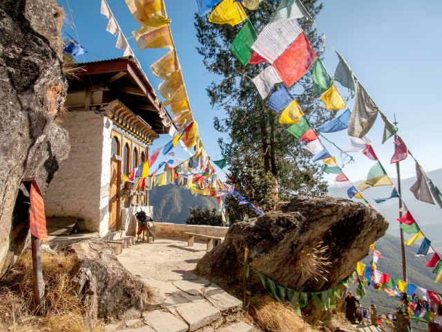 Colorful flags flying over cliffside temple of Paro Taktsang in Bhutan