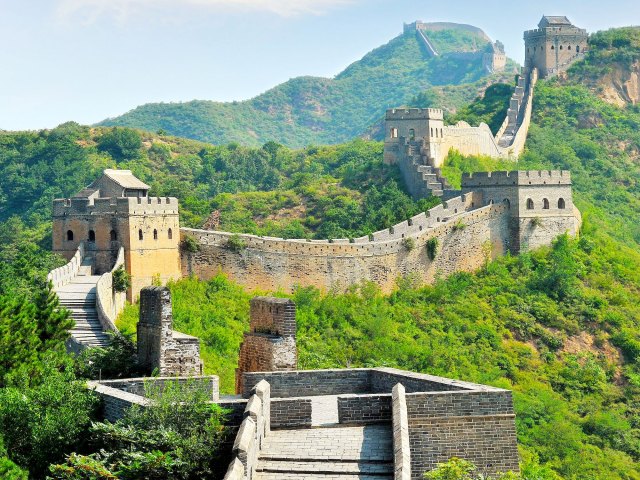 Great Wall of China winding through hilly, tree-covered landscape