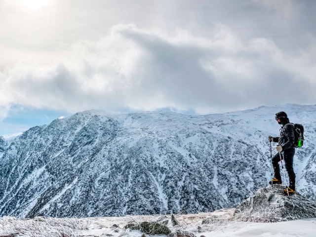 Hiker looking out over snow covered landscape in the White Mountains of New Hampshire