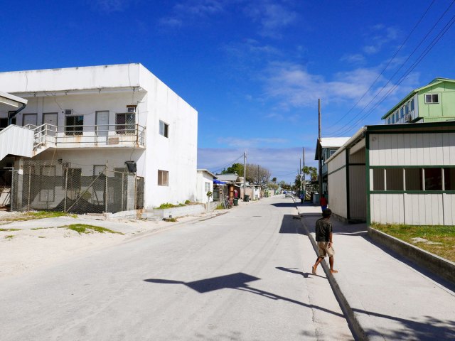 Person walking on street lined with homes in the Marshall Islands