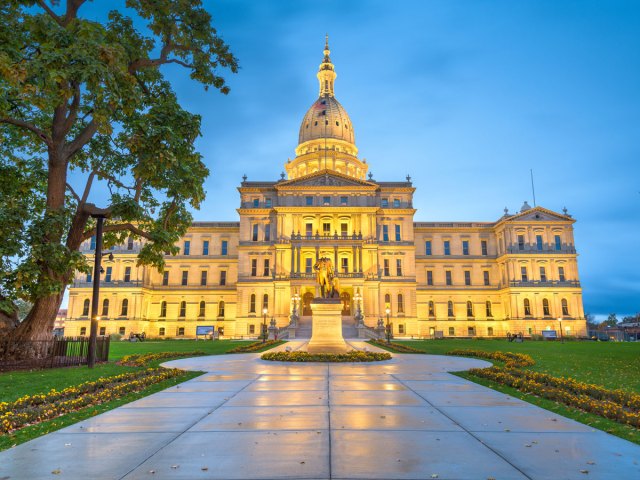 View of statue in front of Michigan State Capitol at dusk