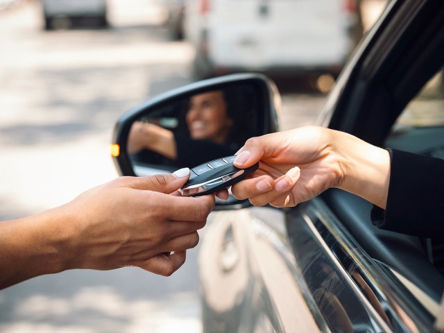 Close-up image of person handing another person keys in car