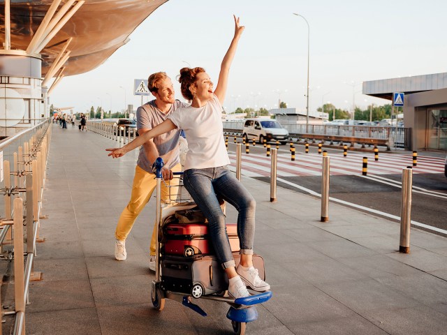 Couple with luggage cart outside of airport