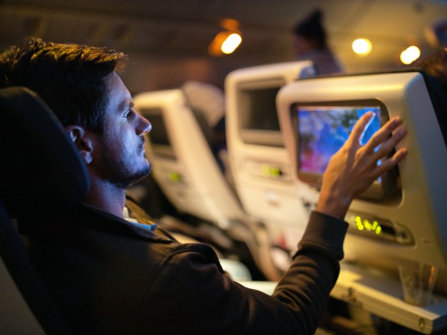 Passenger using seatback entertainment screen on night flight