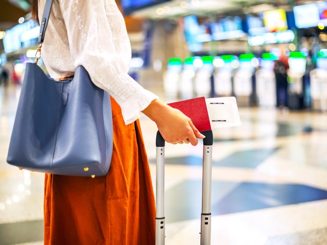 Traveler holding boarding pass and luggage at airport