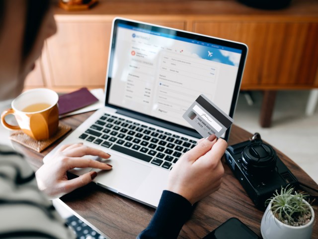 Person holding credit card in front of laptop