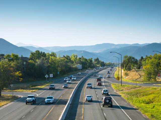 Cars on highway surrounded by mountains, seen from above