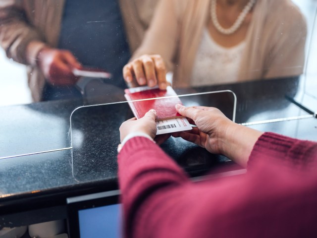 Zoomed-in image of passenger handing ticket and passport to airport agent