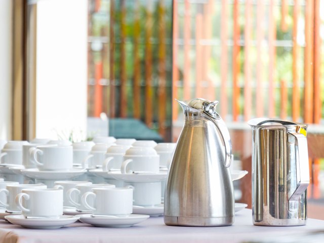 Carafes of coffee and stacks of coffee cups in hotel restaurant