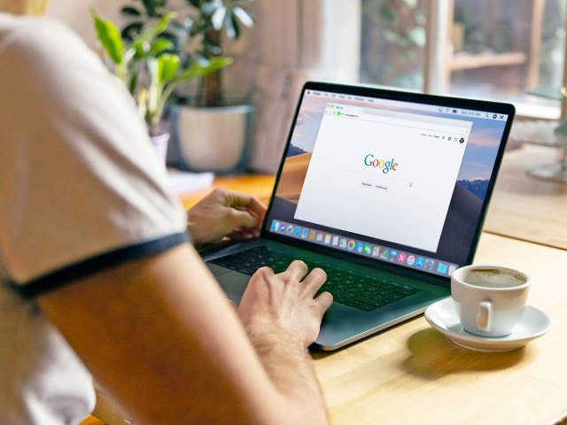 Close-up of person using Google on laptop computer