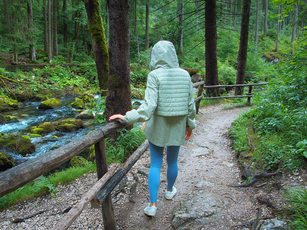 Person wearing sneakers on muddy walking trail, seen from behind