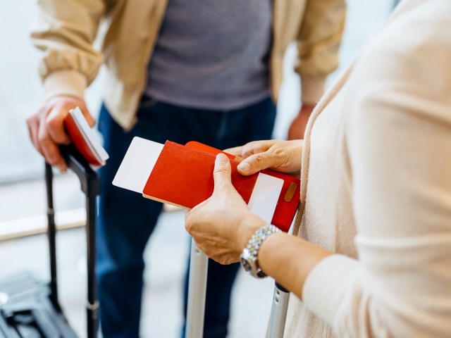 Zoomed-in image of passengers holding passports and airplane tickets