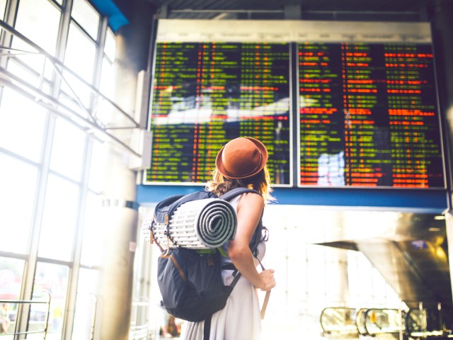 Traveler looking at flight departure and arrivals board at airport