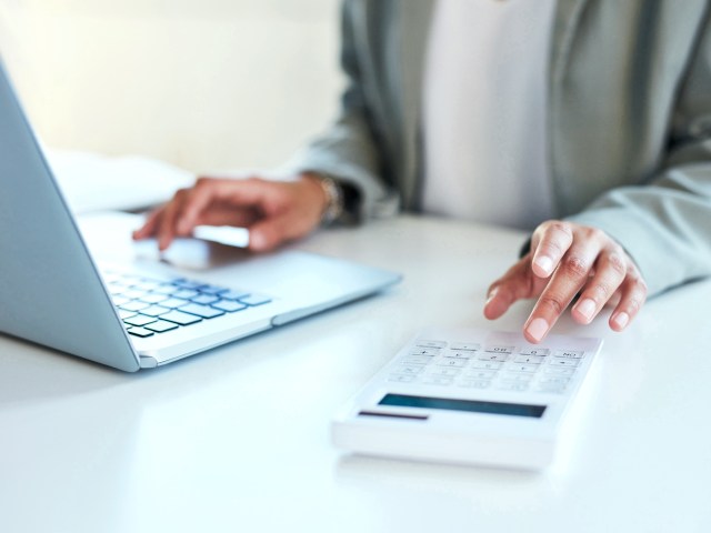 Zoomed-in image of person working with laptop computer and calculator