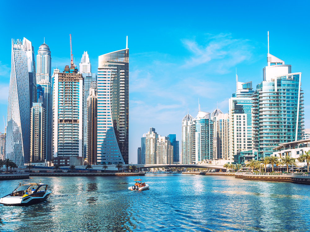 Boats in river between skyscrapers in Dubai, UAE