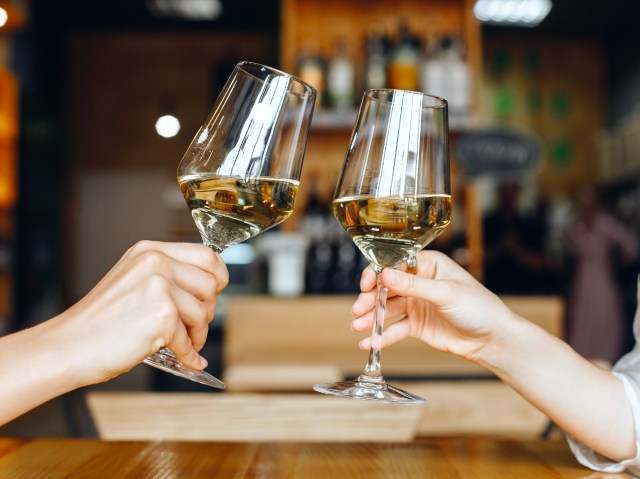 Travelers in airport clinking wine glasses