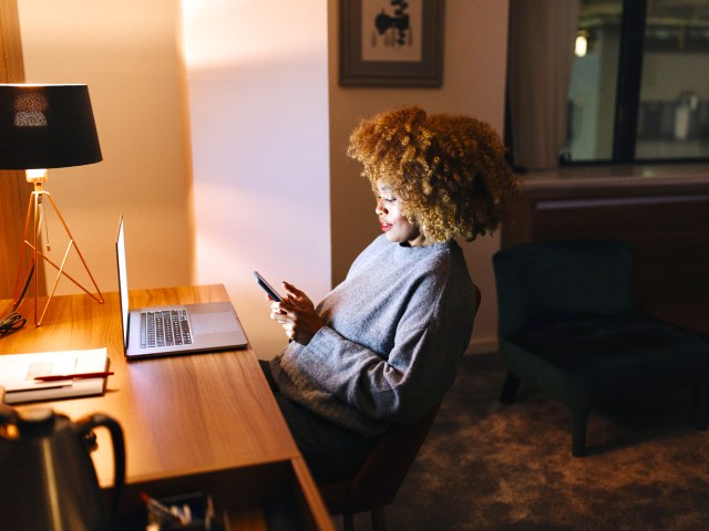 Person at desk using cellphone and laptop computer