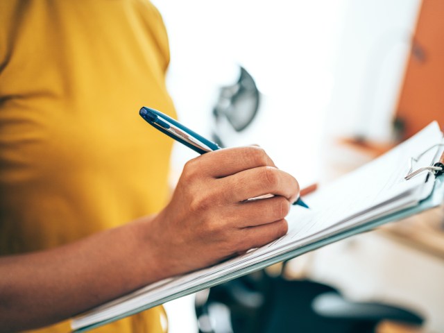 Close-up image of person writing on clipboard