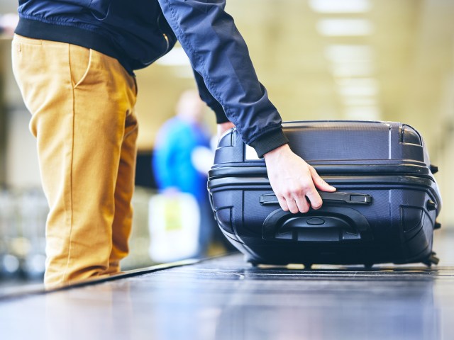 Passenger picking up suitcase from luggage carousel