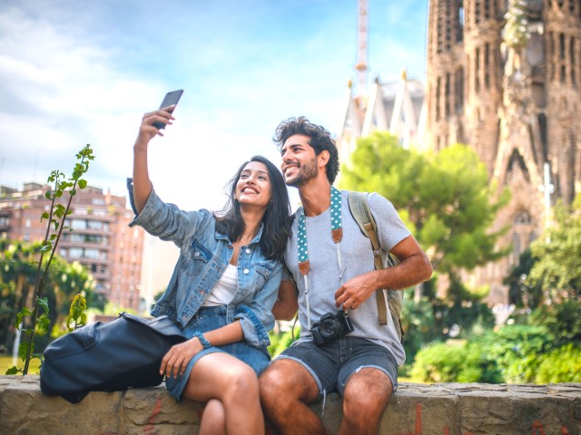 Couple taking self in front of La Sagrada Familia church in Barcelona, Spain