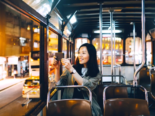 Bus rider taking photo out of window with cellphone