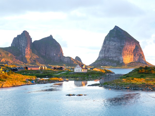 Home on small island with towering rock formations in background in northern Norway