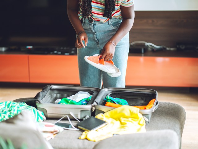 Traveler packing sandals into suitcase