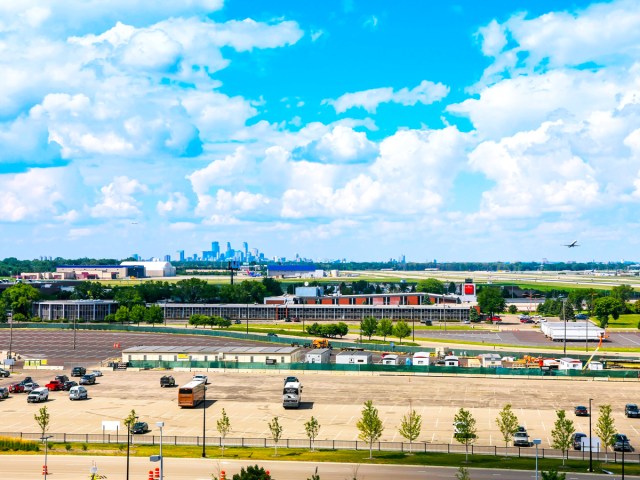 Overview of parking lot and plane taking off from runway at Minneapolis-St. Paul International Airport