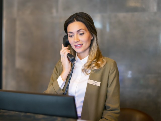 Hotel front desk staff member speaking on phone