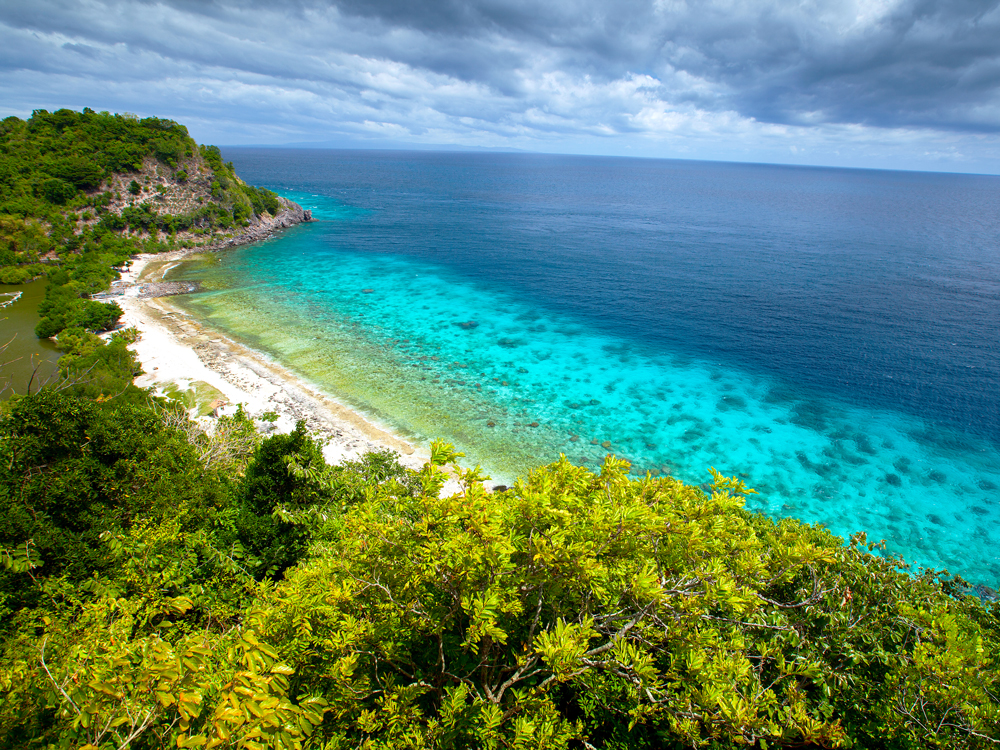 Turquoise waters off sandy beach in Apo Reef Natural Park in the Philippines, seen from above