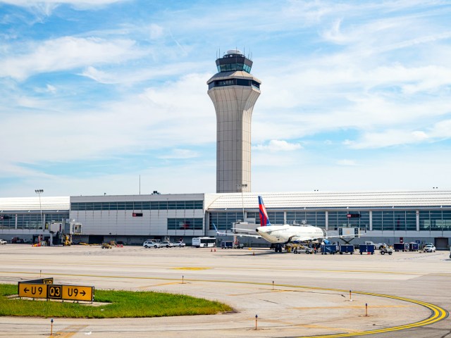 Plane parked at gate beneath control tower at Detroit Metropolitan Wayne County Airport