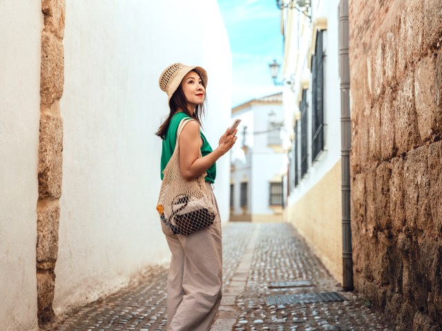 Traveler holding phone and walking down narrow cobblestone street