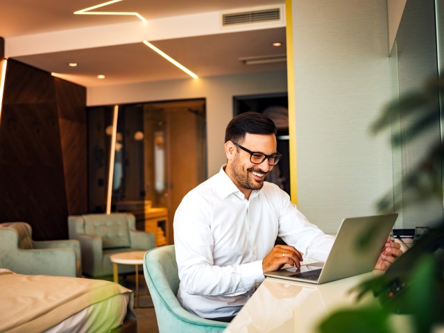 Person at desk in hotel room using laptop computer