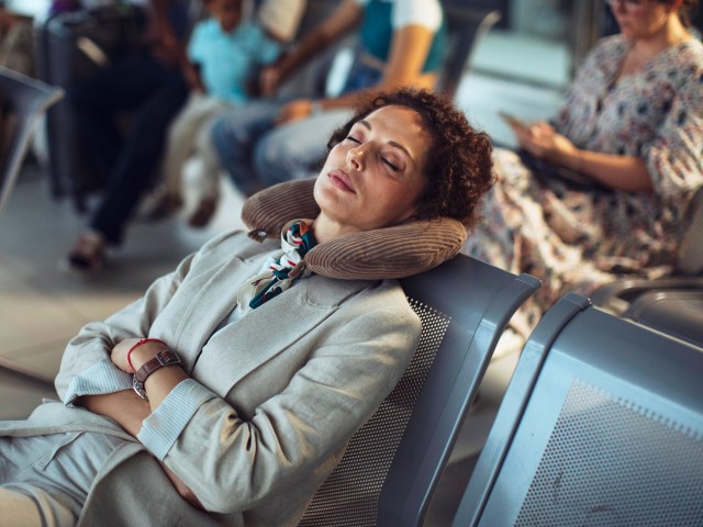 Passenger resting with neck pillow in airport terminal