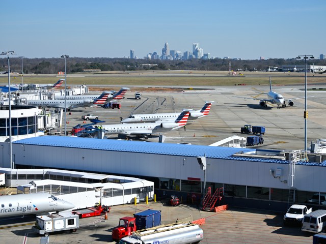 Planes on tarmac with city skyline in background at Charlotte International Airport