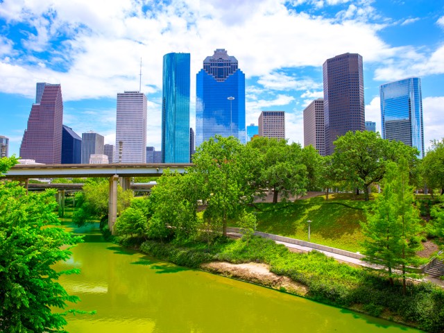 River and park with Houston skyscrapers looming overhead