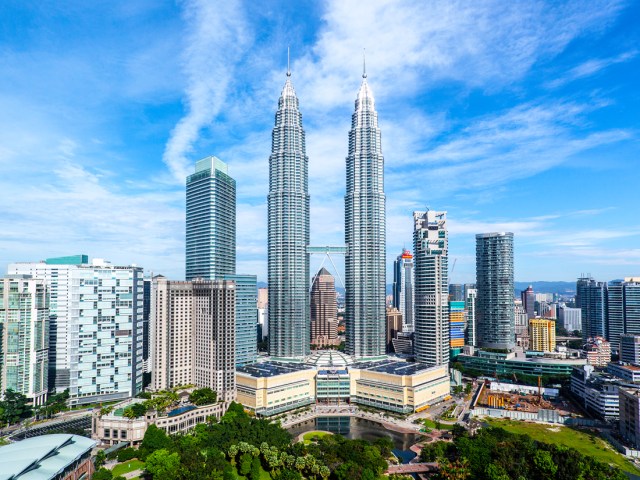 Petronas Towers, connected by bridge in middle, surrounded by other skyscrapers in Kuala Lumpur, Malaysia