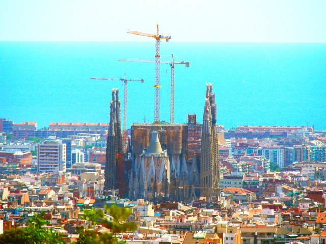 View of construction cranes over the Sagrada Família and Barcelona skyline facing the Mediterranean Sea