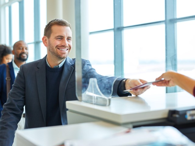 Airline passenger handing ticket and identification to agent at airport