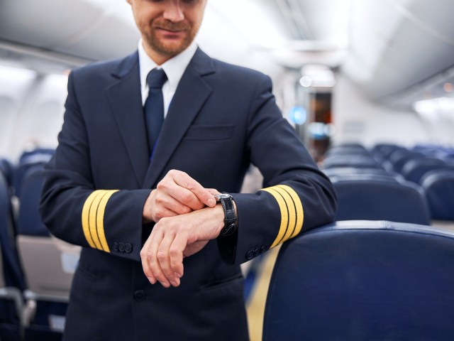 Flight attendant standing in aircraft cabin checking watch