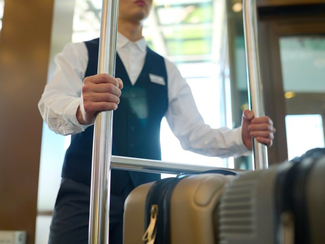 Porter rolling luggage on cart in hotel