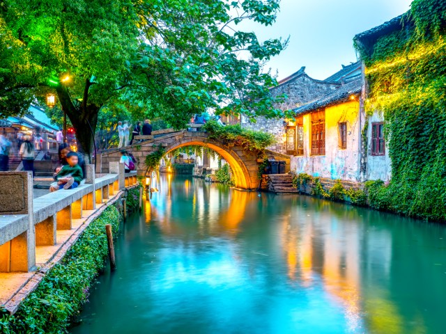 Canal lined with stone homes covered in ivy in Zhouzhuang, China