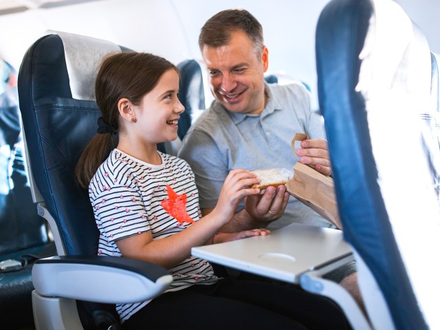 Father and daughter sharing in-flight meal