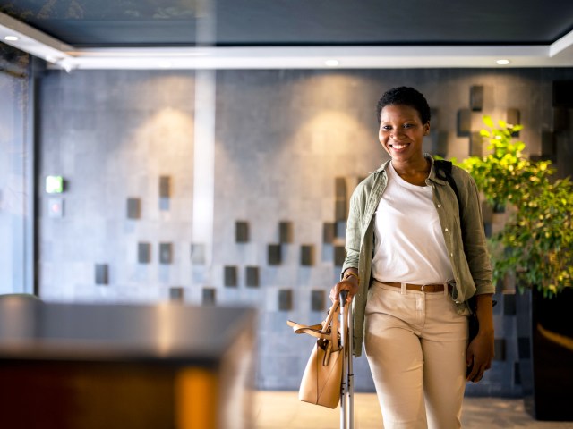 Traveler rolling suitcase in hotel lobby